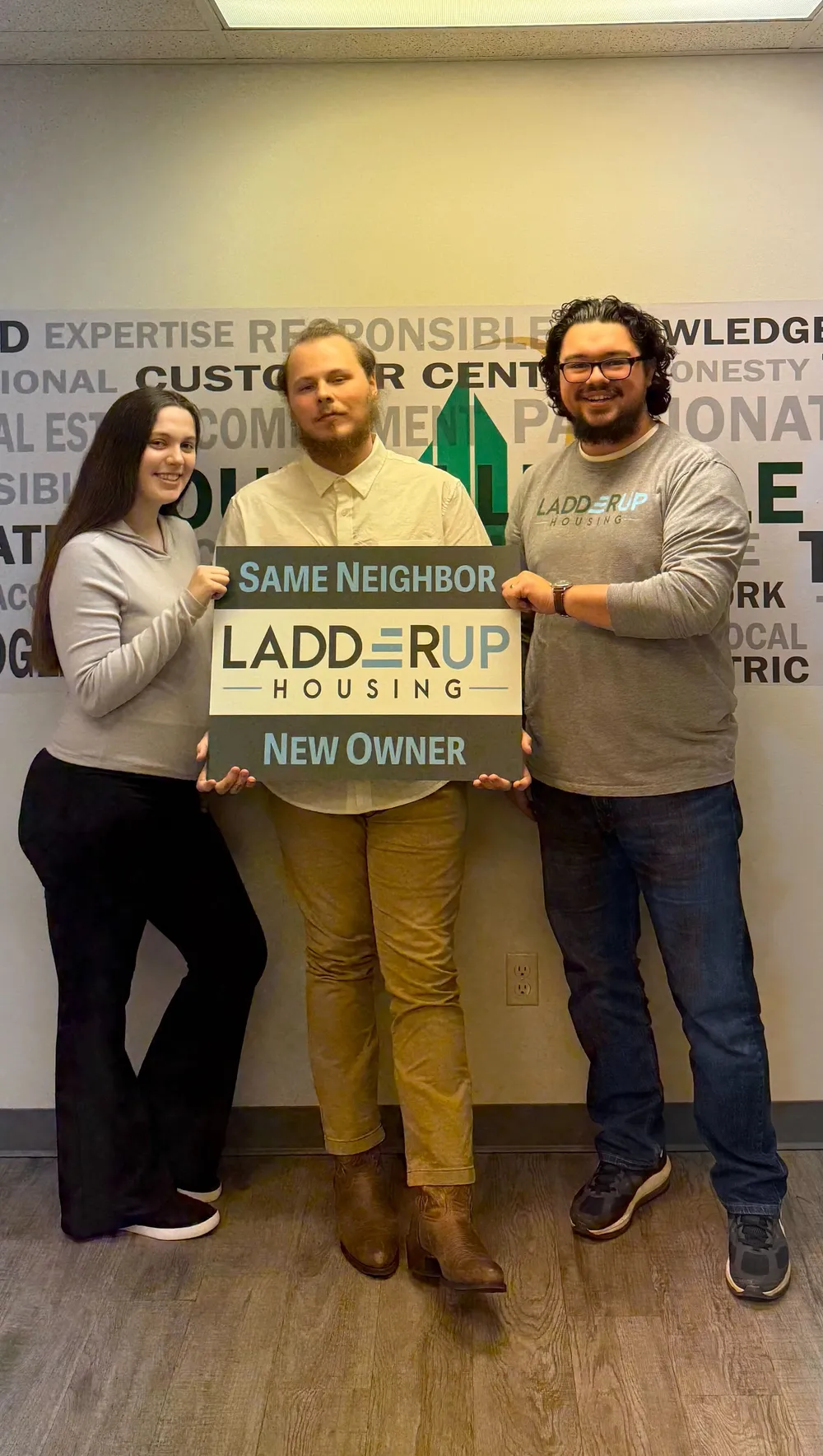 Tristen and Caroline hold Same Neighbor New Owner sign after purchasing their home through LadderUp Housing in Toledo, Ohio